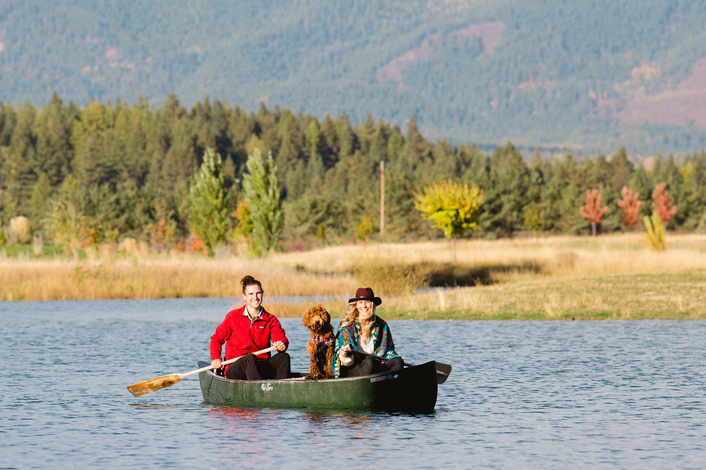 couple and dog canoeing on pond
